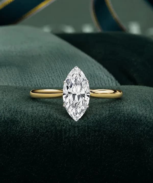 Marquise lab grown diamond cathedral solitaire engagement ring in yellow gold on green velvet