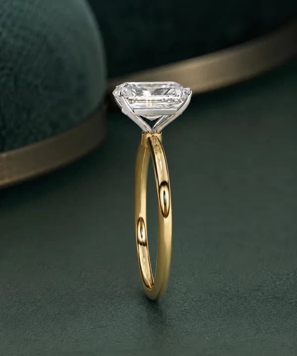 Radiant cut lab grown diamond four-claw solitaire engagement ring in yellow gold on green velvet