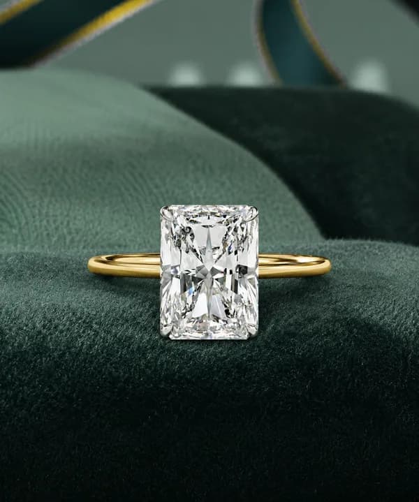 Radiant cut lab grown diamond four-claw solitaire engagement ring in yellow gold on green velvet