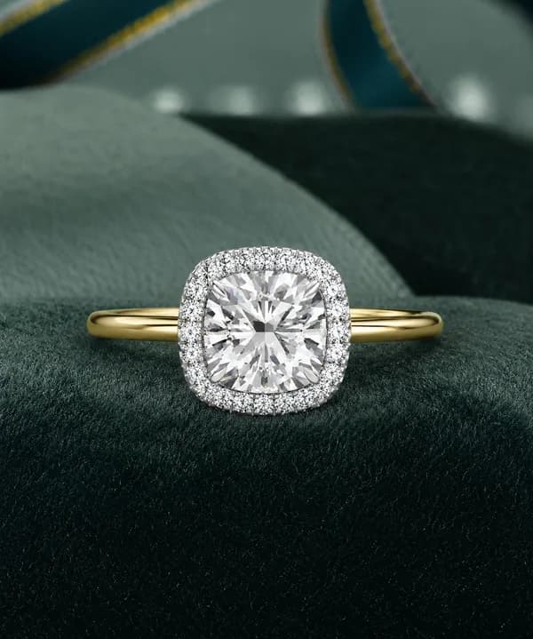 Cushion cut lab grown diamond halo engagement ring in yellow gold on a green velvet cushion