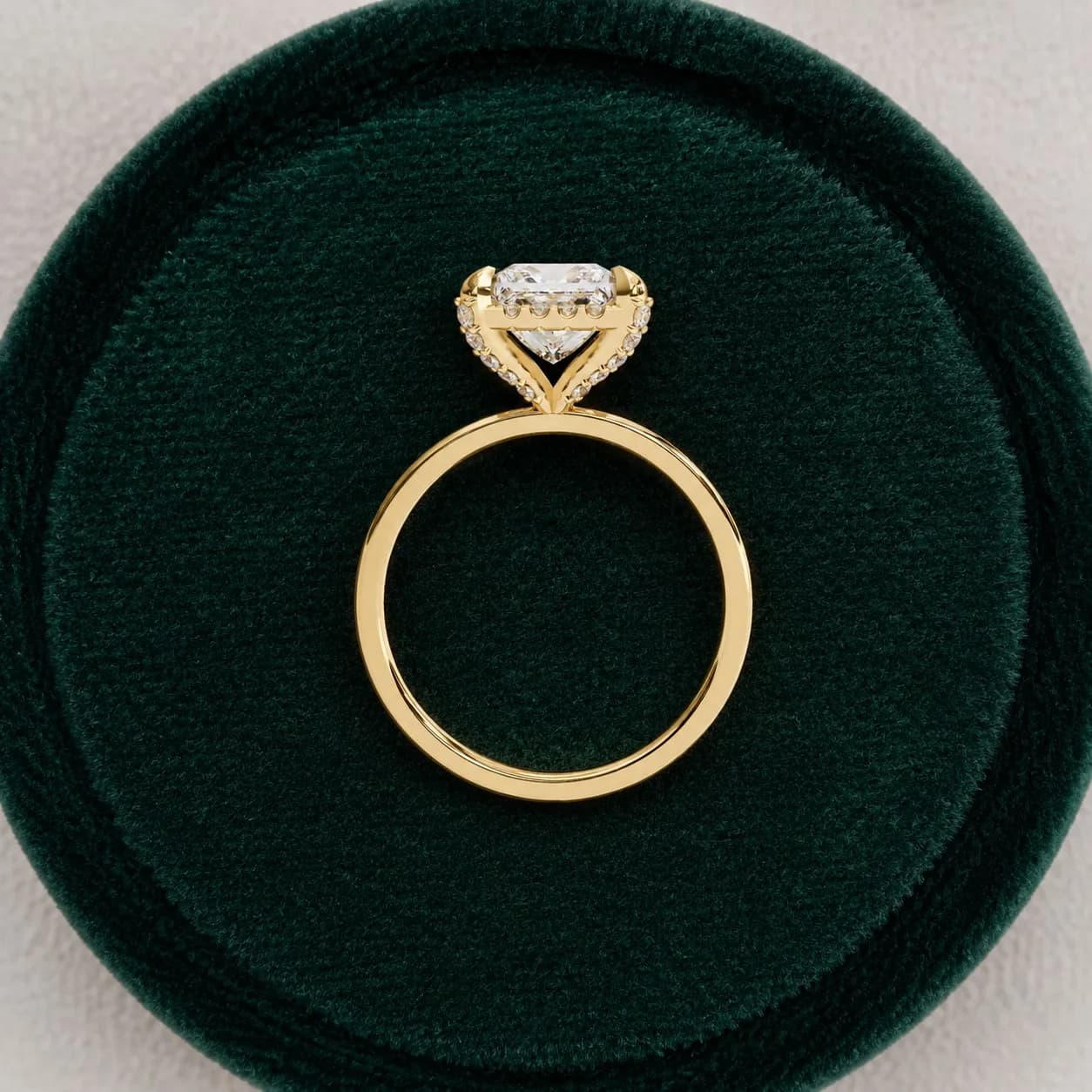 Princess cut lab grown diamond low halo engagement ring in yellow gold in a green velvet ring box