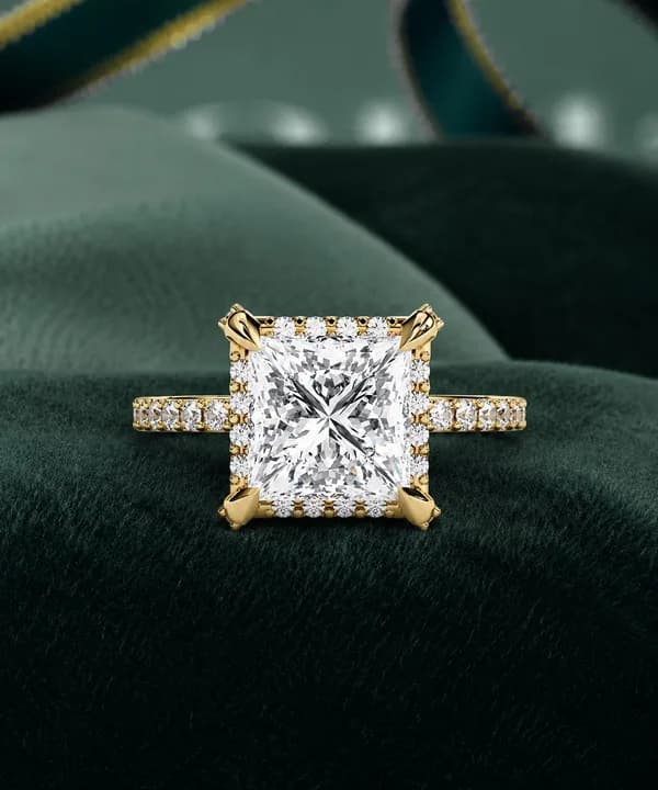 Princess cut lab grown diamond halo engagement ring in yellow gold on green velvet