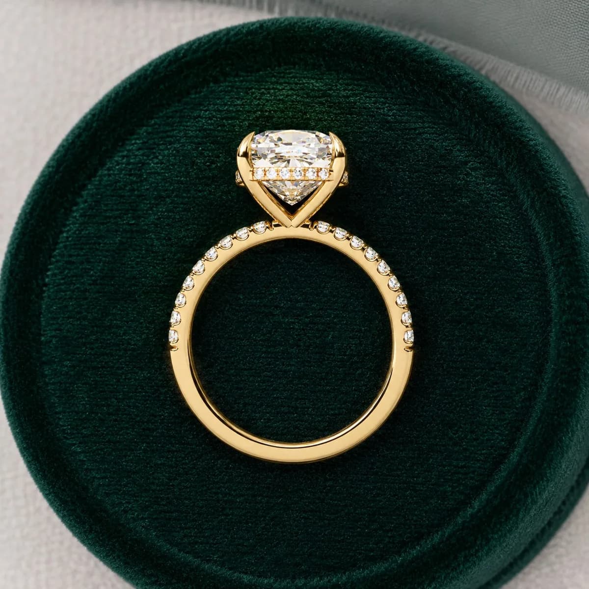 Cushion cut lab grown diamond hidden halo engagement ring in yellow gold in a green velvet ring box