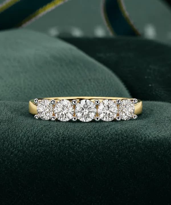 Round lab grown diamond five-stone wedding band in yellow gold on green velvet