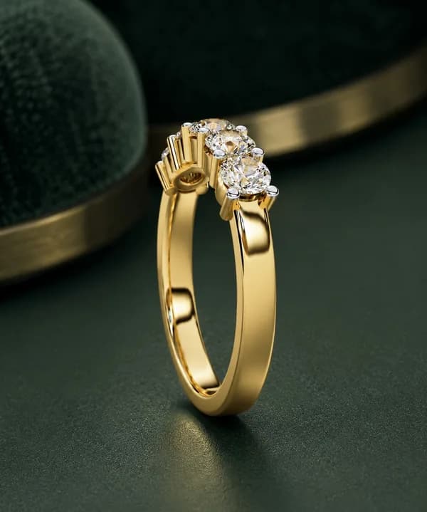 Round lab grown diamond five-stone wedding band in yellow gold on green velvet