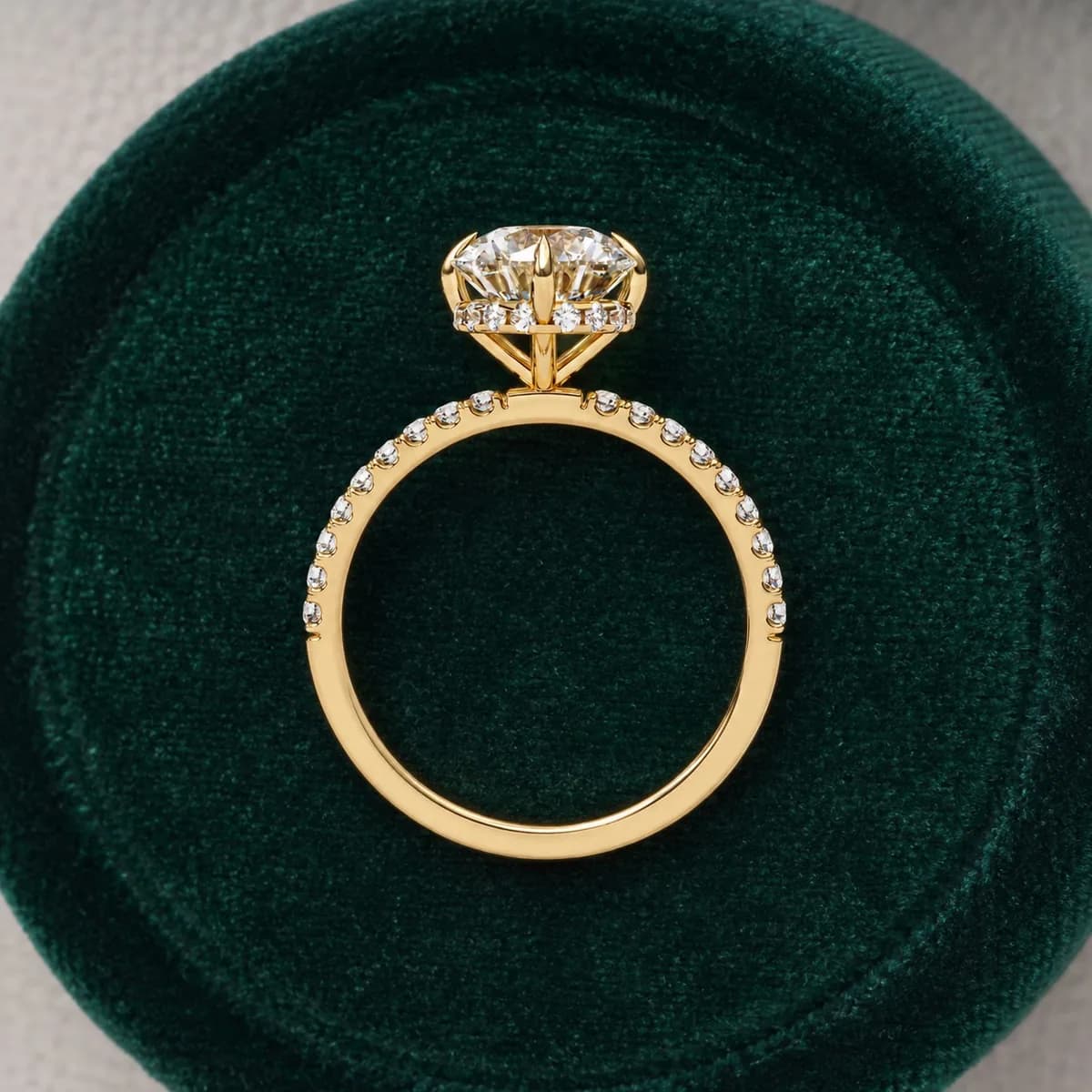 Round lab grown diamond compass prong hidden halo engagement ring in yellow gold standing in a green velvet ring box