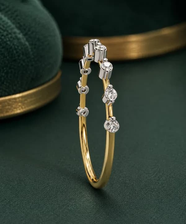 Round lab grown diamond station wedding band in yellow gold standing on a green velvet display
