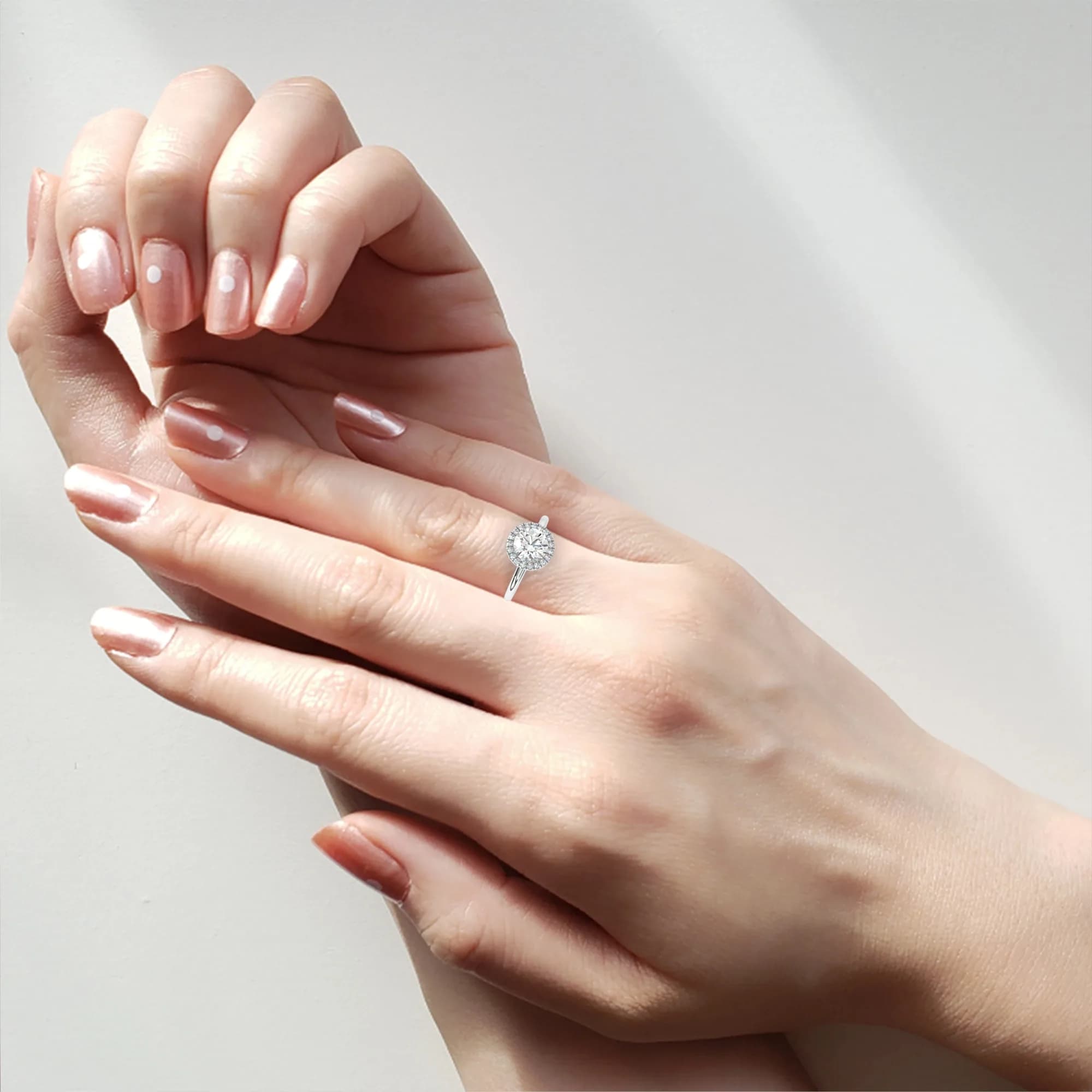 Round lab grown diamond halo engagement ring with plain band worn on a woman's hand