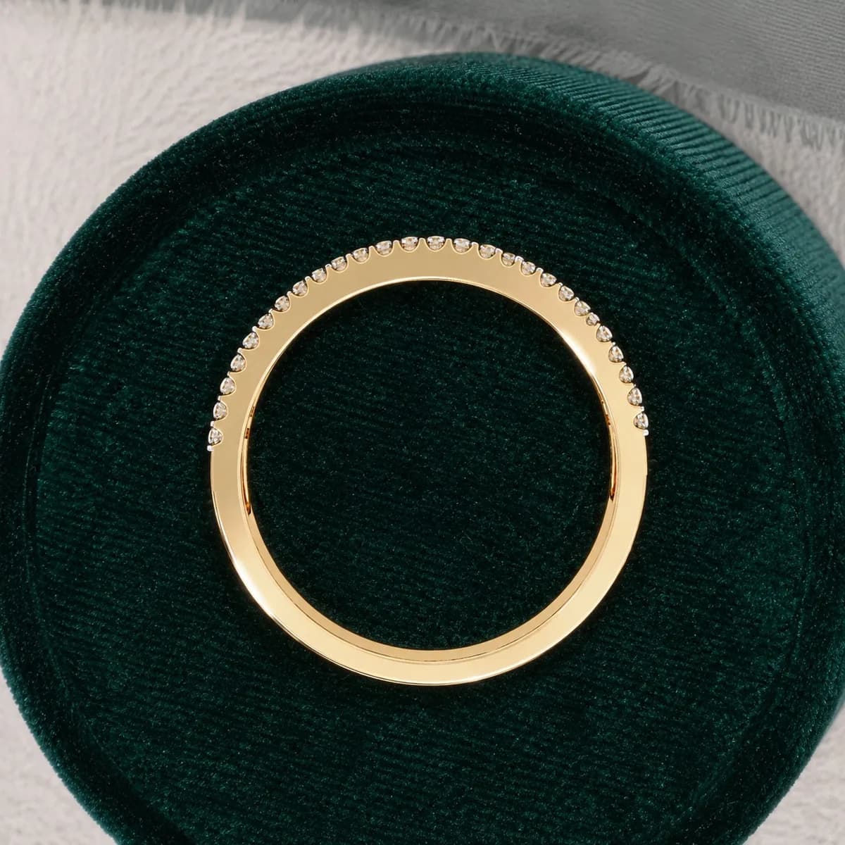 Baguette and round lab grown diamond three-row wedding band in yellow gold in a green velvet ring box