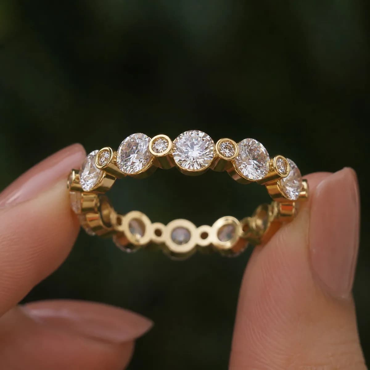 Round lab grown diamond alternating full eternity band in yellow gold held between fingertips