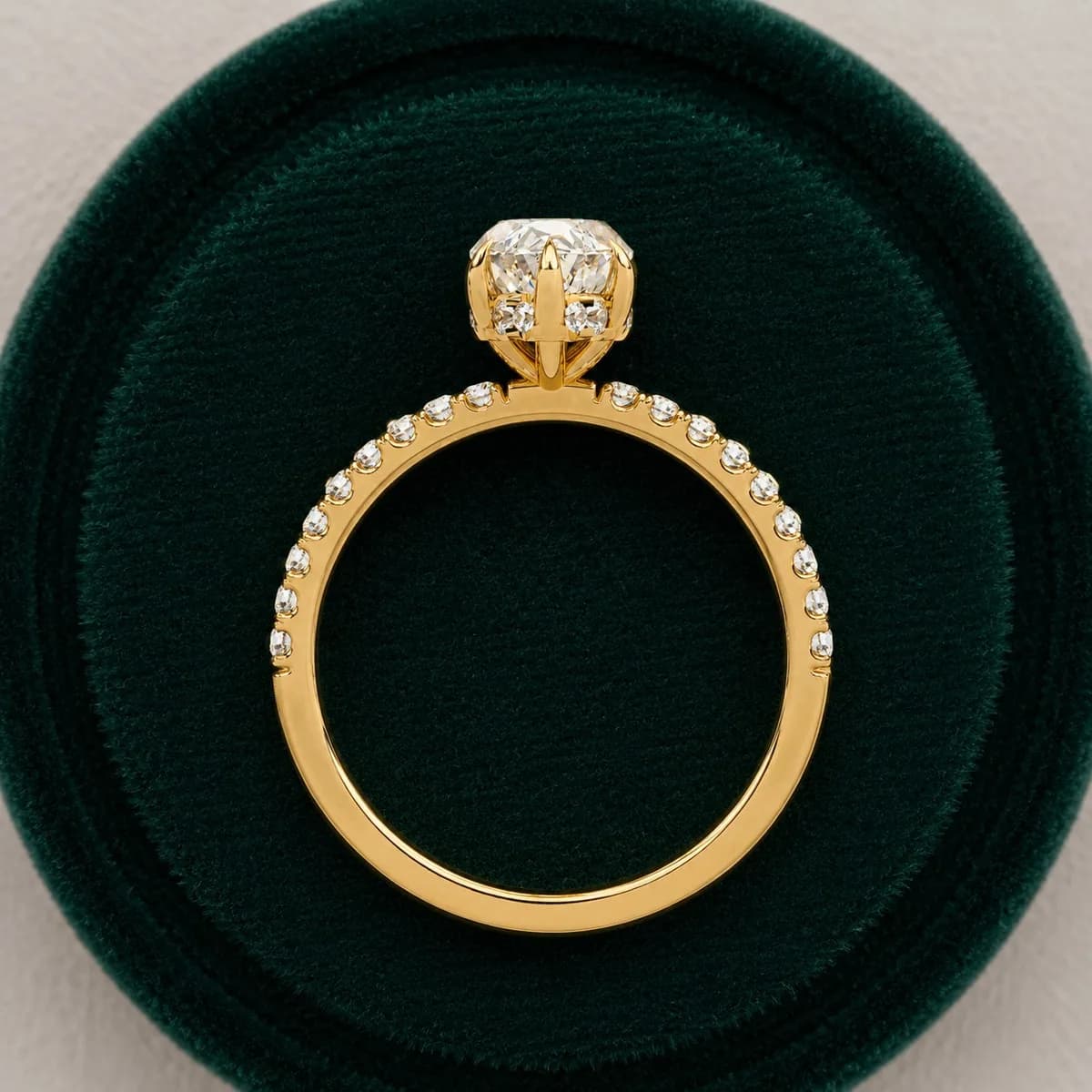 Marquise cut lab grown diamond hidden halo engagement ring with pavé band in yellow gold standing in a green velvet ring box