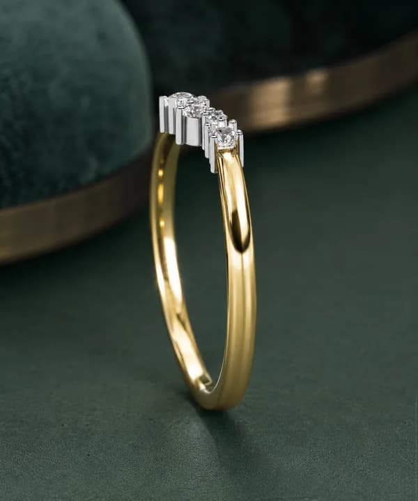Round lab grown diamond curved crown wedding band in yellow gold standing on a green velvet display