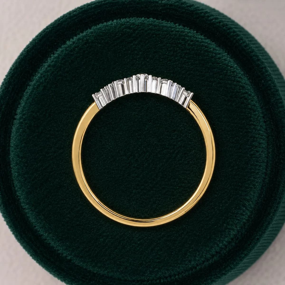 Round lab grown diamond curved crown wedding band in yellow gold standing in a green velvet ring box
