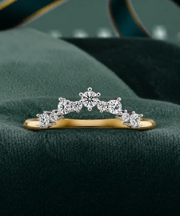 Round lab grown diamond curved crown wedding band in yellow gold resting on green velvet