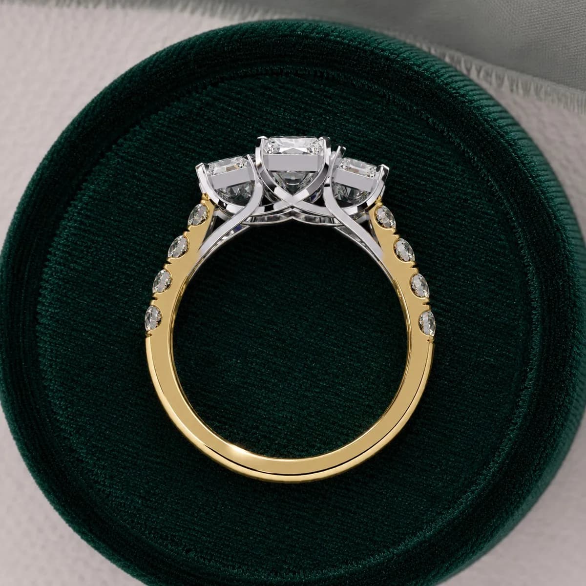Radiant cut lab grown diamond three-stone engagement ring in yellow gold in a green velvet ring box