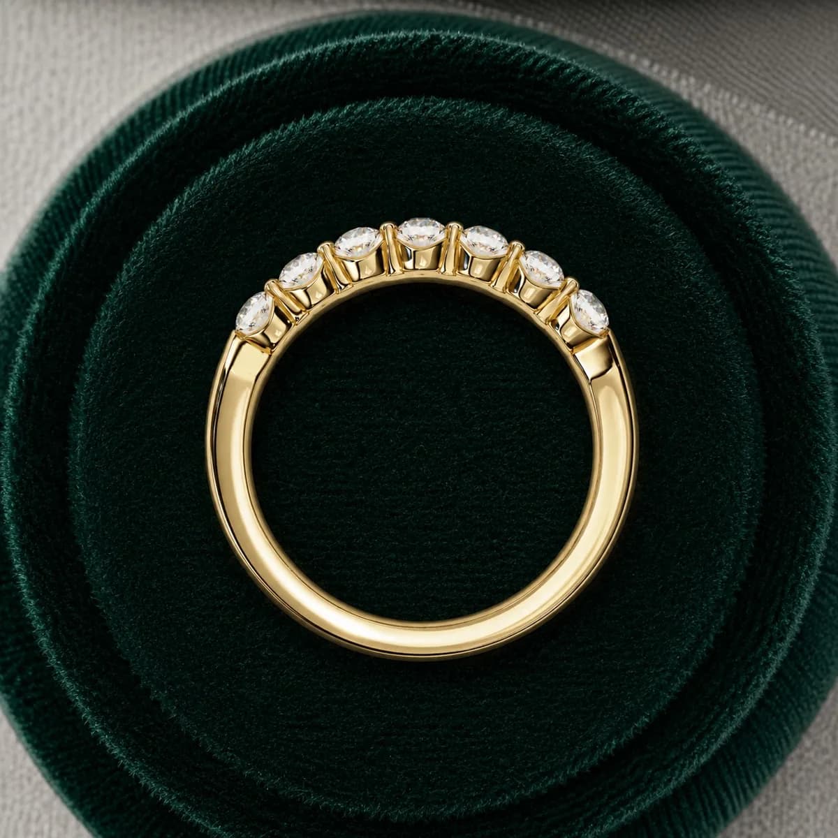Round lab grown diamond seven-stone wedding band in yellow gold standing in a green velvet ring box