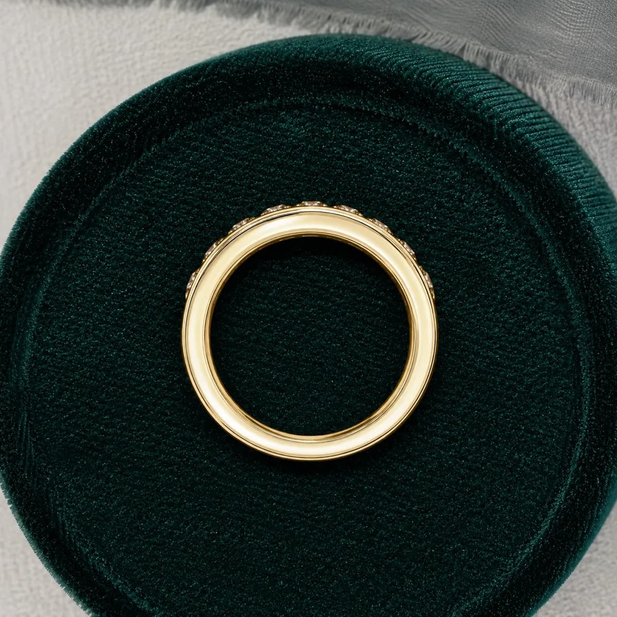 Princess cut lab grown diamond channel-set half eternity band in yellow gold standing in a green velvet ring box