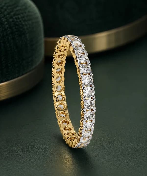 Round lab grown diamond full eternity wedding band in yellow gold standing upright on green velvet, side view