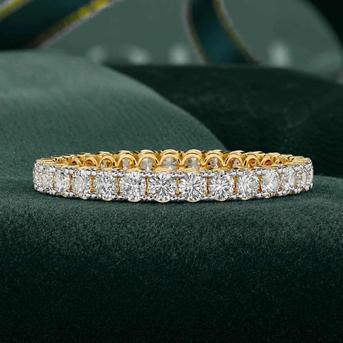 Round lab grown diamond full eternity wedding band in yellow gold resting on green velvet