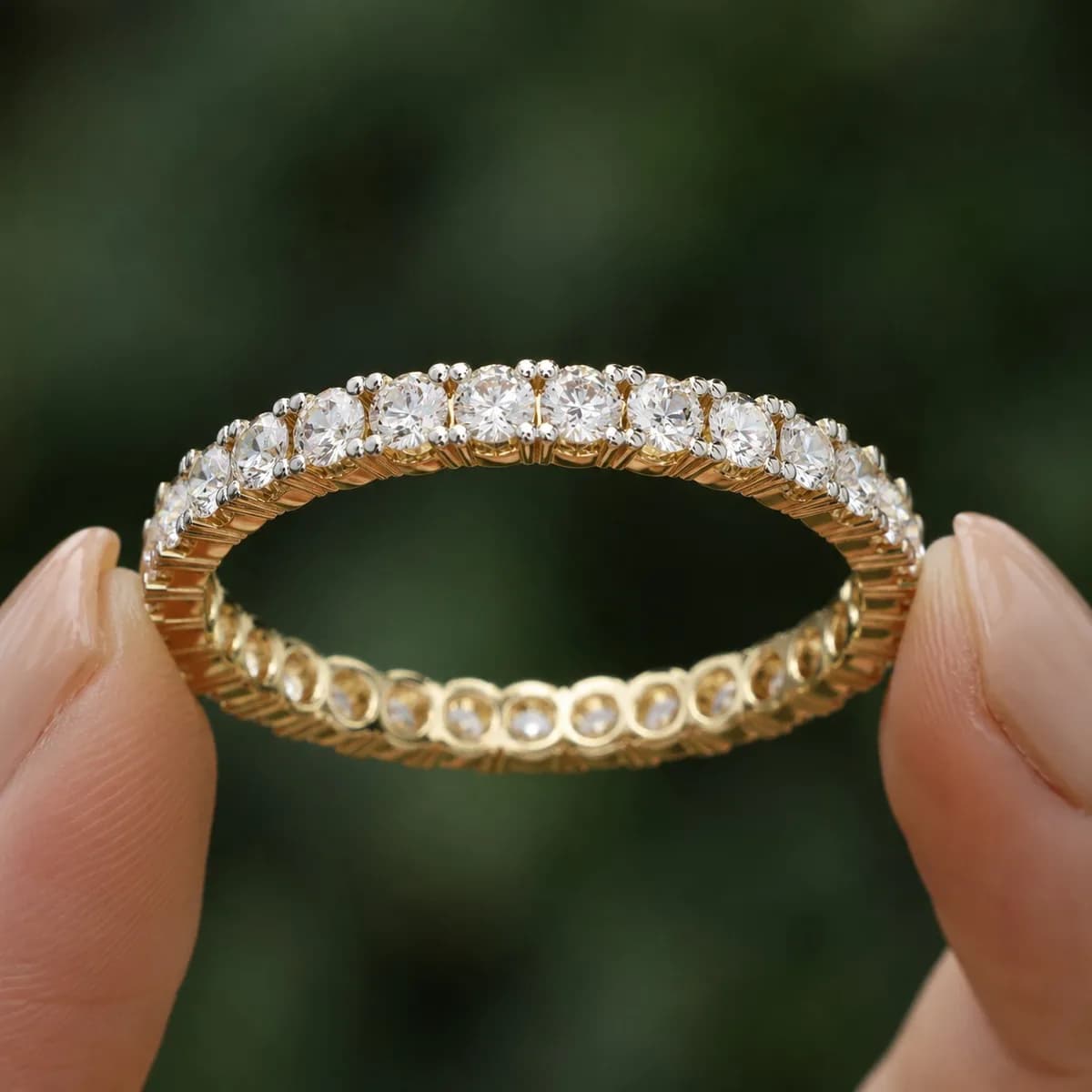 Round lab grown diamond full eternity wedding band in yellow gold held between fingertips