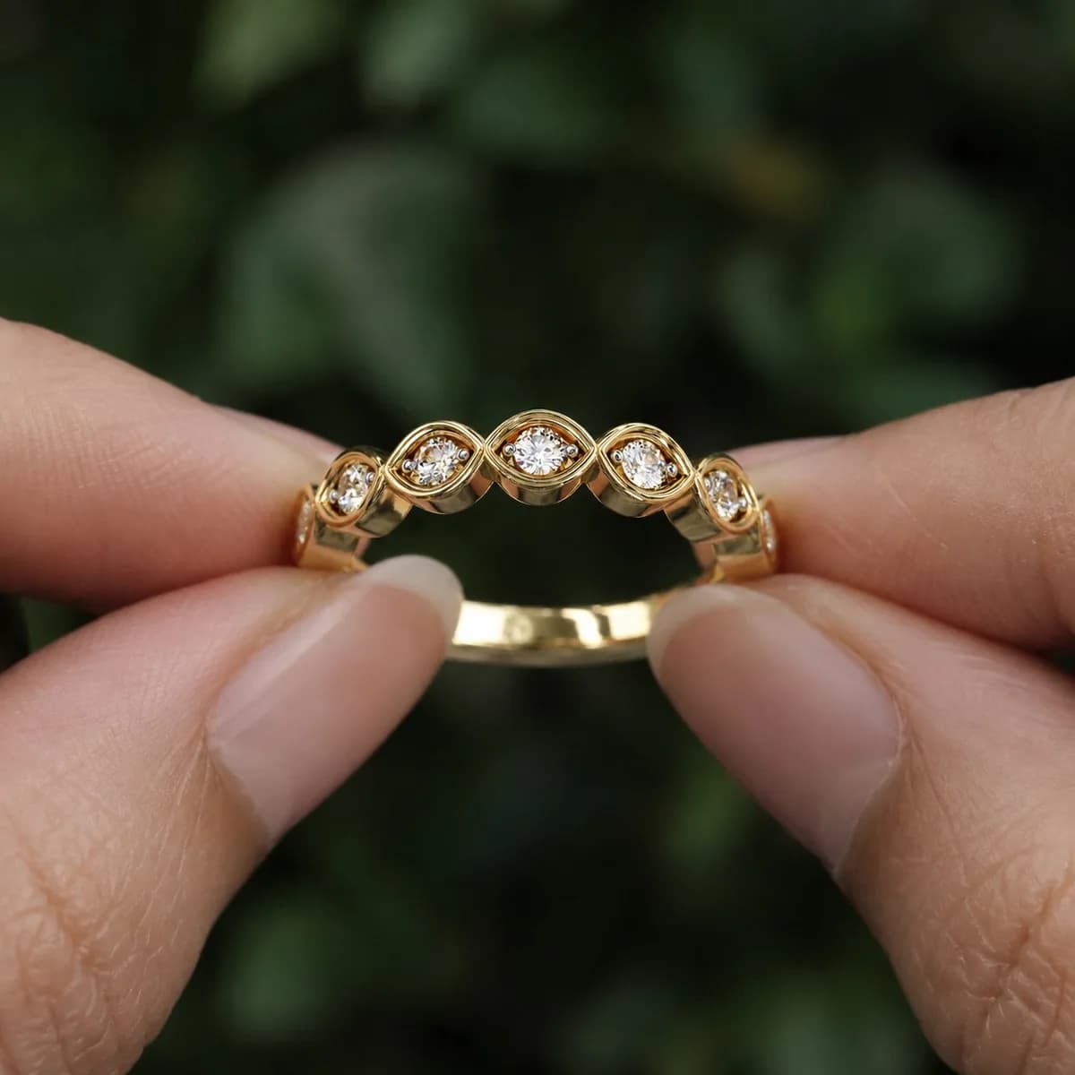 Round lab grown diamond marquise frame half eternity wedding band in yellow gold held between fingertips