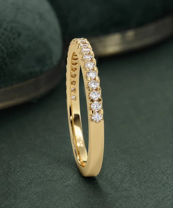 Round lab grown diamond pavé half eternity band in yellow gold standing on green velvet, side view