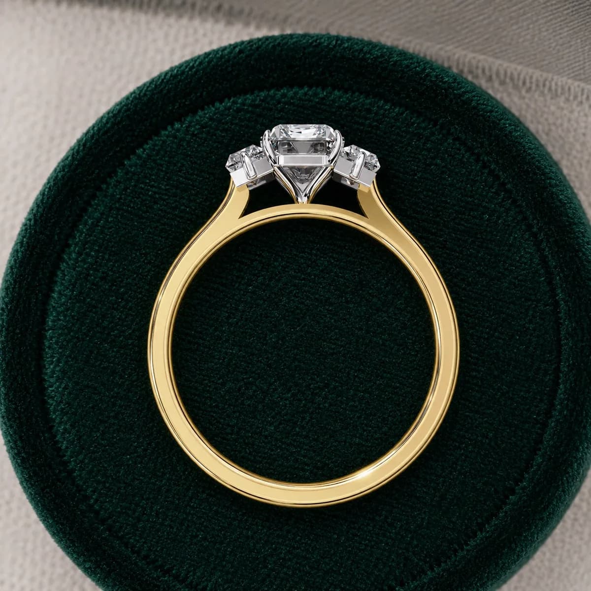 Emerald cut lab grown diamond three-stone engagement ring in yellow gold in a green velvet ring box