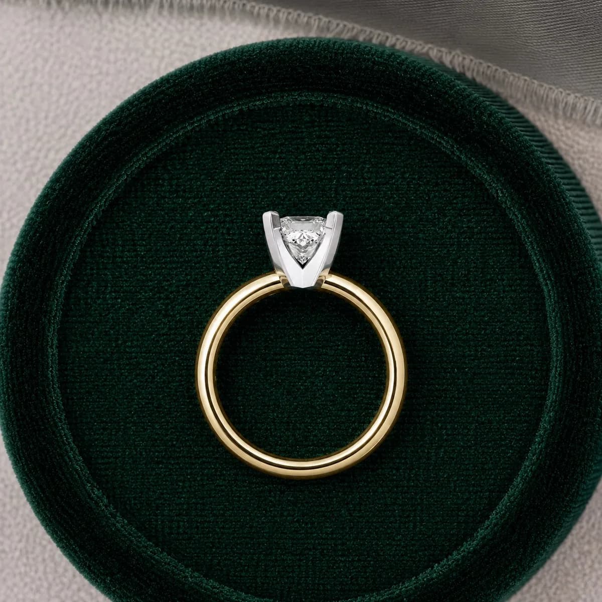 Princess cut lab grown diamond knife-edge solitaire engagement ring in yellow gold in a green velvet ring box