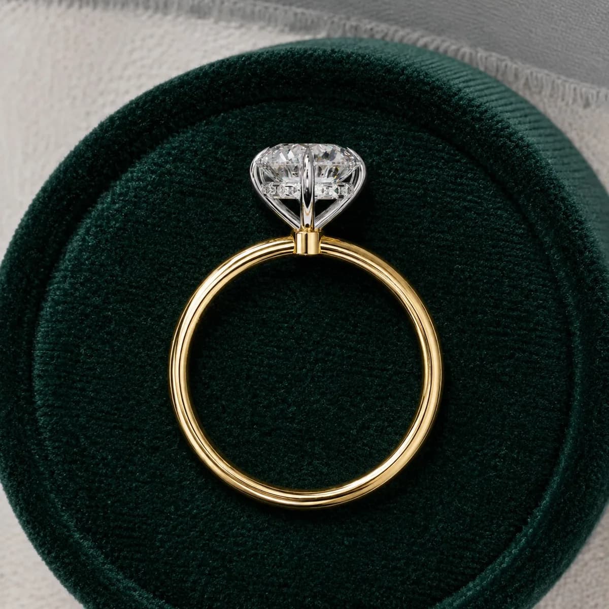 Round lab grown diamond compass prong solitaire engagement ring in yellow gold in a green velvet ring box