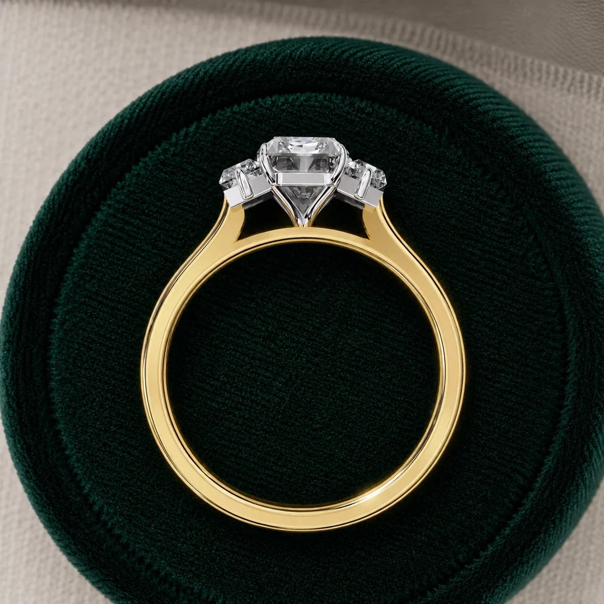 Radiant cut lab grown diamond three-stone engagement ring in yellow gold standing in a green velvet ring box
