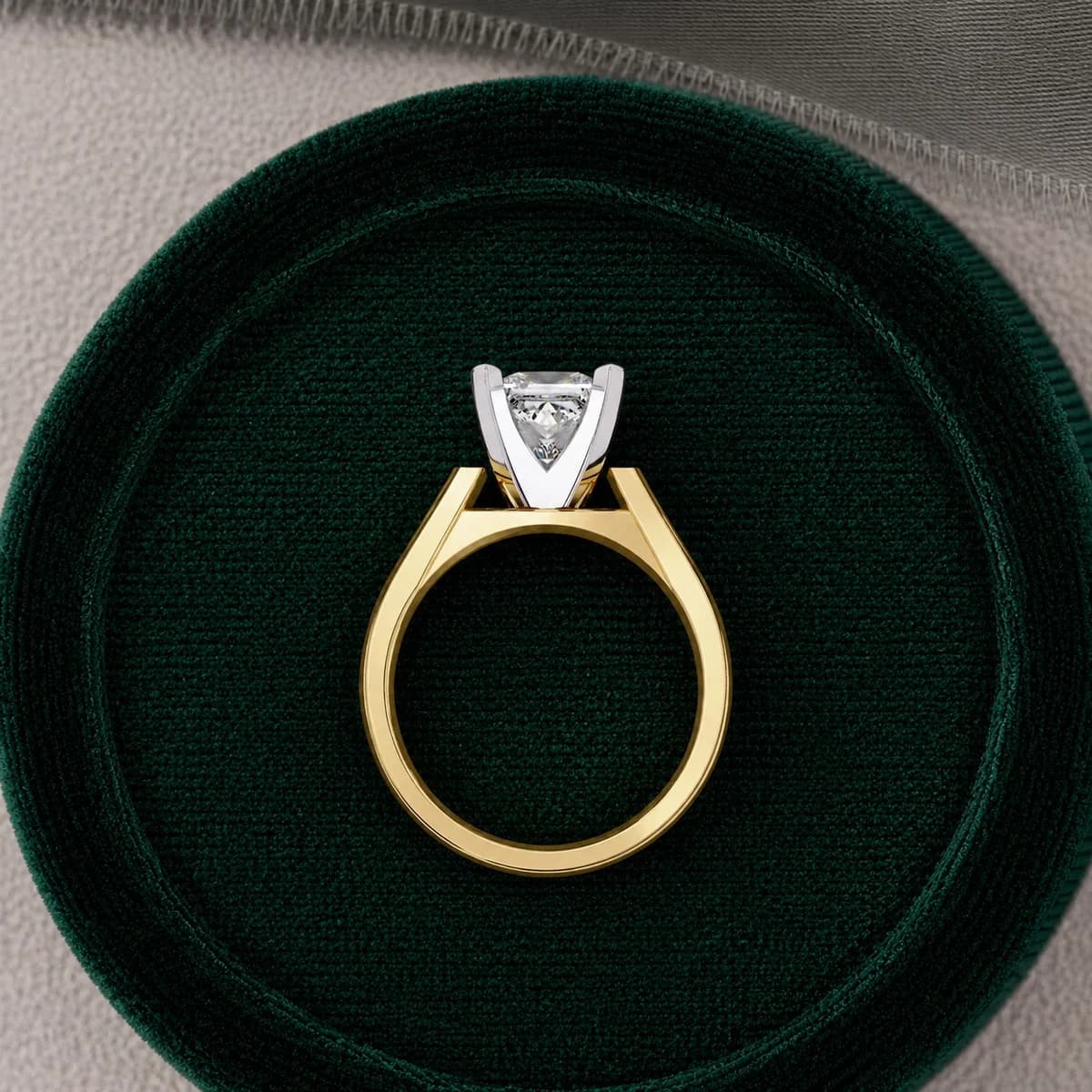 Princess cut lab grown diamond cathedral solitaire engagement ring in yellow gold standing in a green velvet ring box