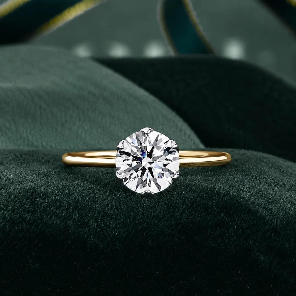 Round lab grown diamond six-prong tulip solitaire engagement ring in yellow gold on green velvet