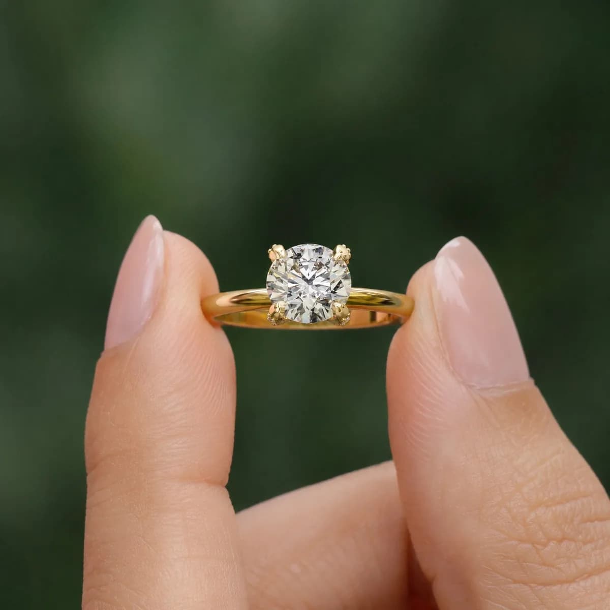 Round lab grown diamond pavé claw solitaire engagement ring in yellow gold held between fingertips