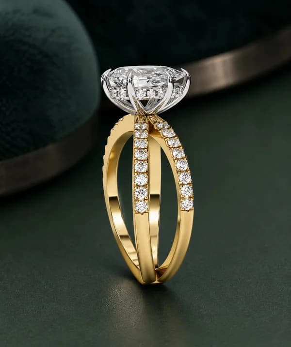 Pear cut lab grown diamond crossover pavé engagement ring in yellow gold standing on a green velvet display