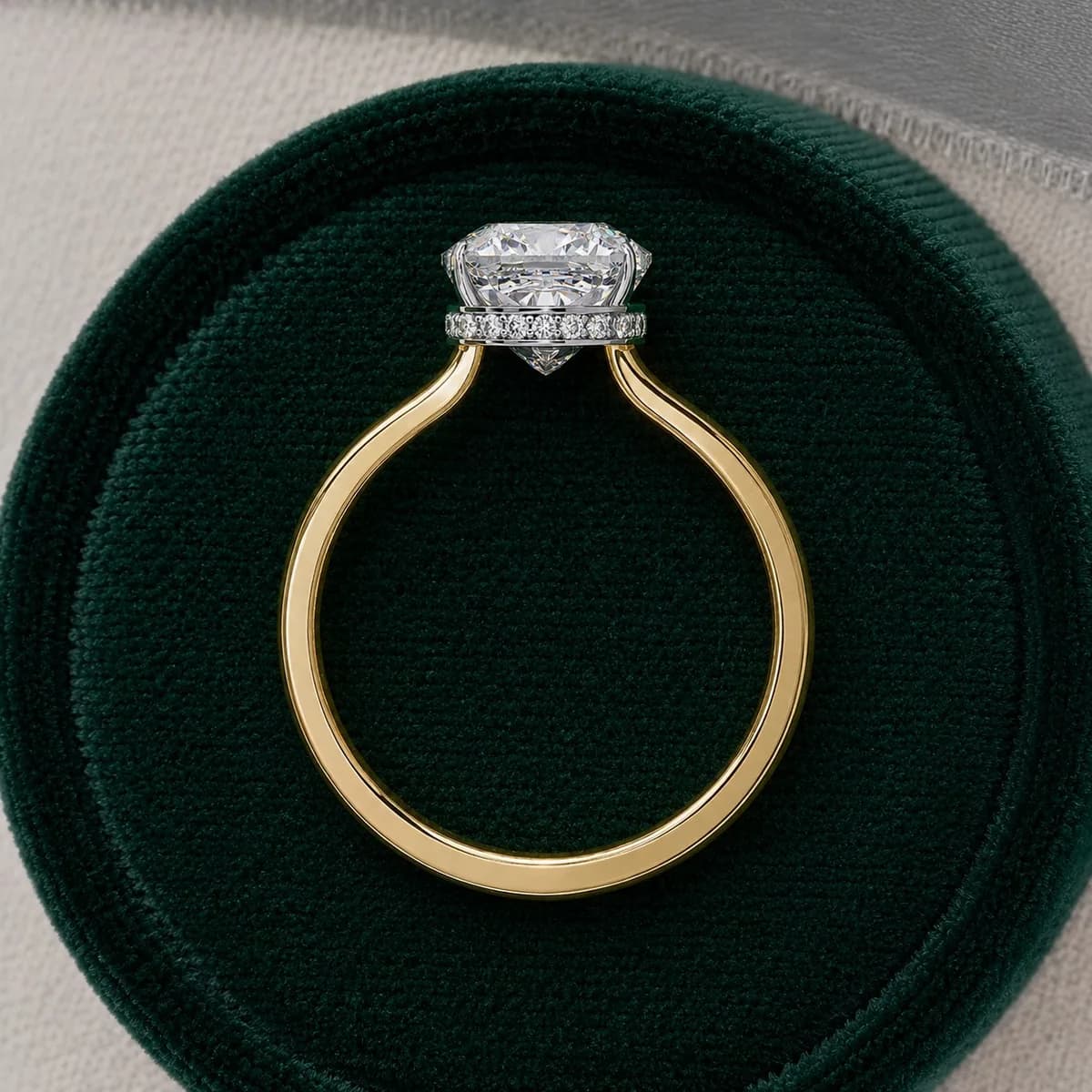 Cushion cut lab grown diamond hidden halo solitaire in yellow gold standing in a green velvet ring box