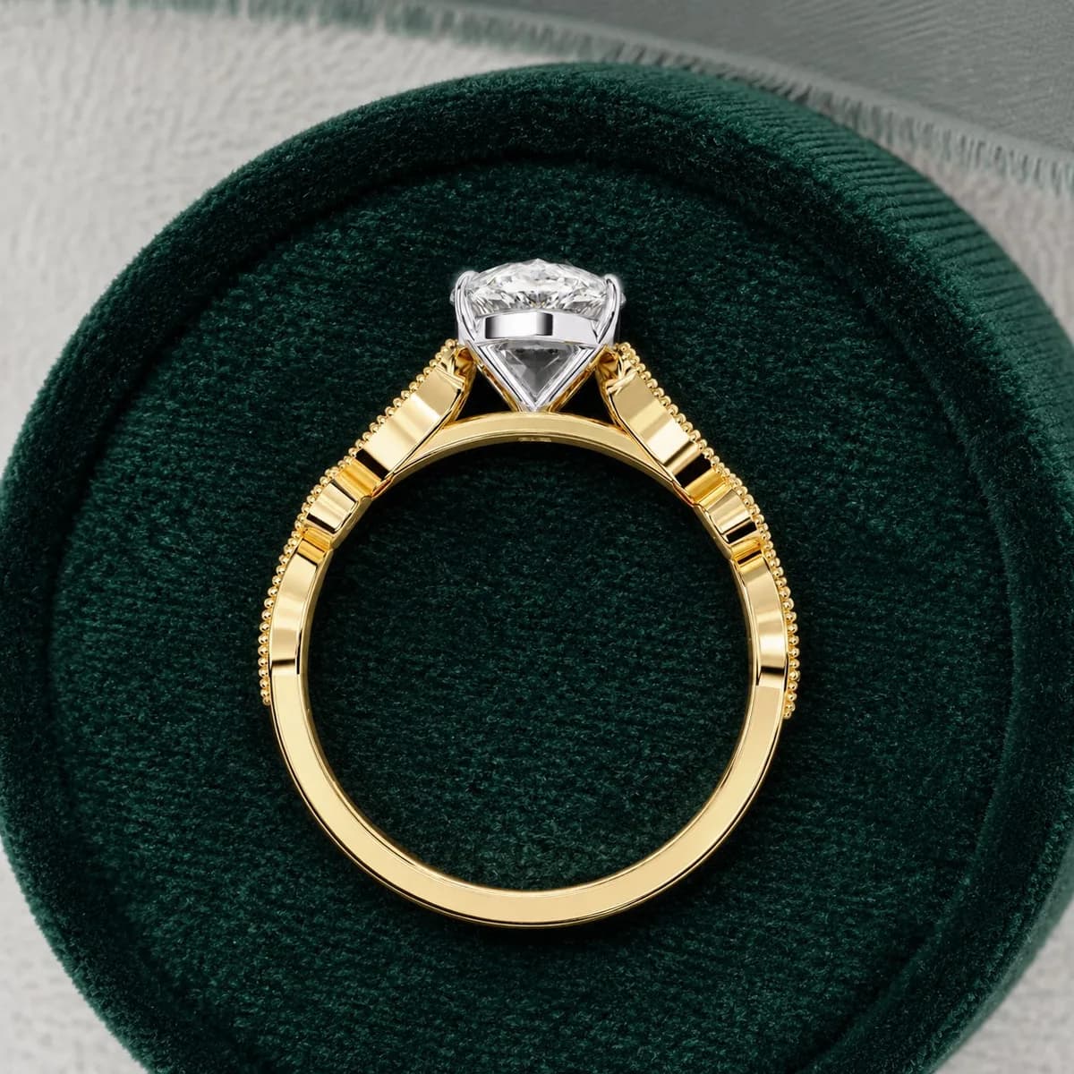 Pear cut lab grown diamond vintage milgrain engagement ring in yellow gold standing in a green velvet ring box