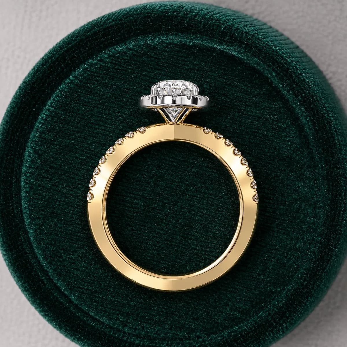 Oval lab grown diamond halo crossover engagement ring in yellow gold in a green velvet ring box