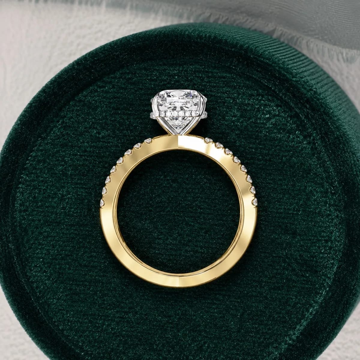 Cushion cut lab grown diamond split shank hidden halo engagement ring in yellow gold standing in a green velvet ring box