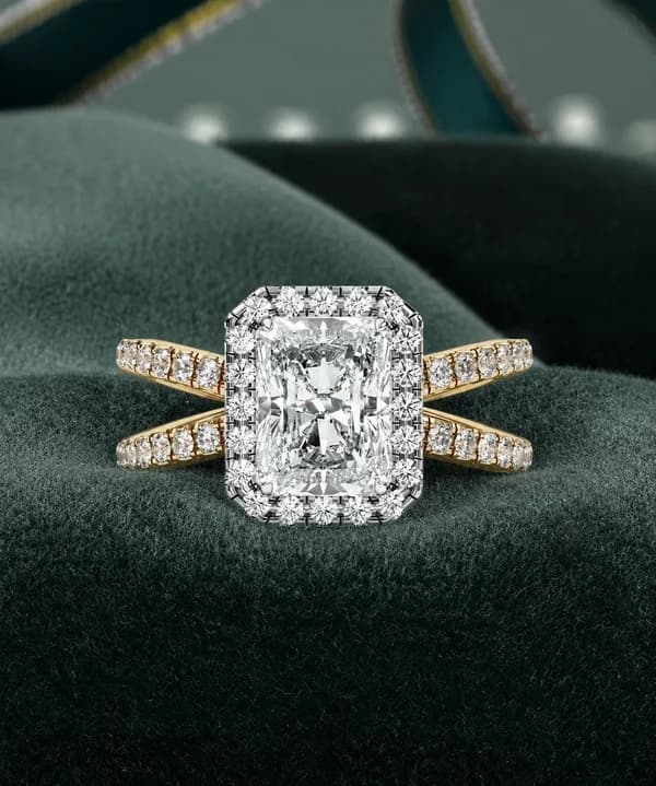 Radiant cut lab grown diamond halo split shank engagement ring in yellow gold resting on green velvet