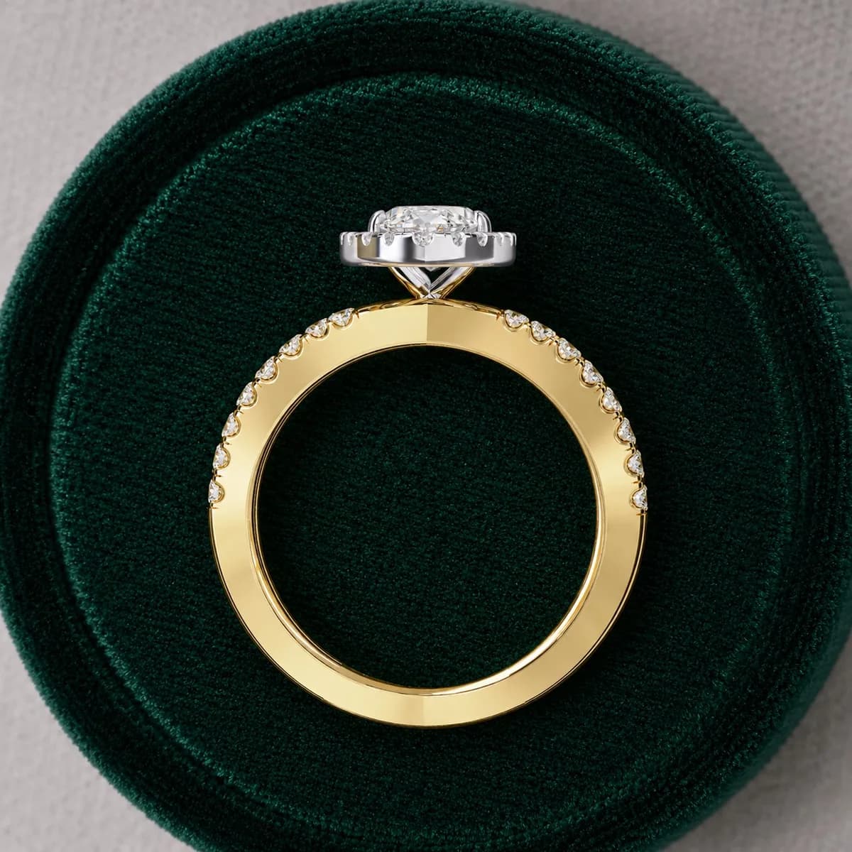 Marquise cut lab grown diamond halo criss-cross engagement ring in yellow gold standing in a green velvet ring box