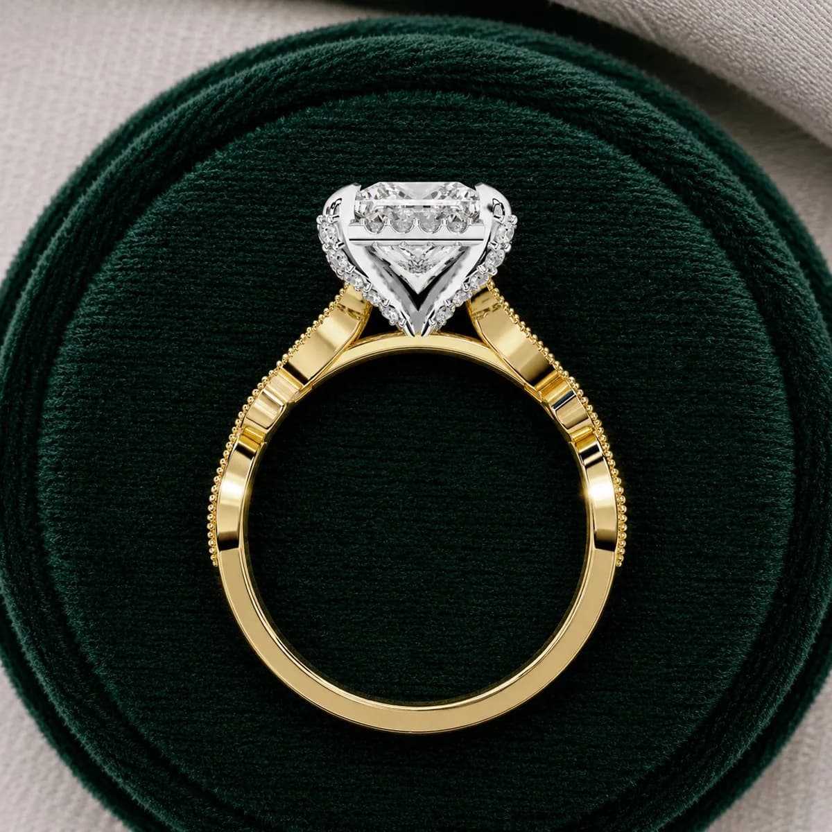 Princess cut lab grown diamond halo engagement ring with vintage band in yellow gold standing in a green velvet ring box