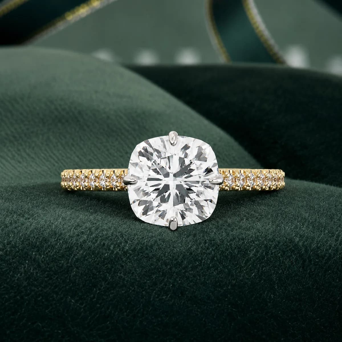 Cushion cut lab grown diamond compass claw hidden halo ring in yellow gold resting on green velvet