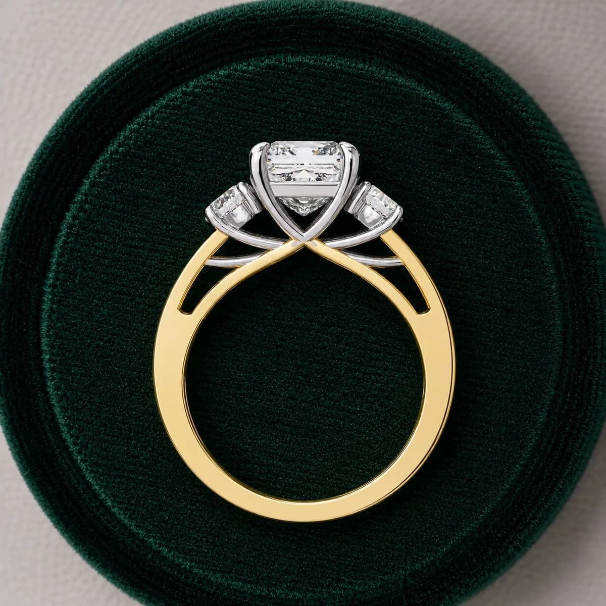 Princess cut lab grown diamond three-stone engagement ring in yellow gold standing in a green velvet ring box