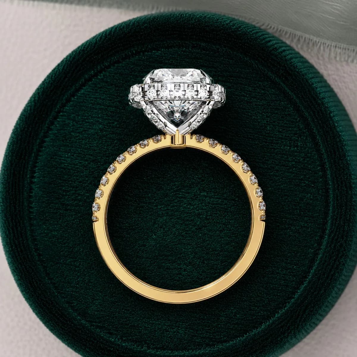 Cushion cut lab grown diamond halo pavé engagement ring in yellow gold standing in a green velvet ring box