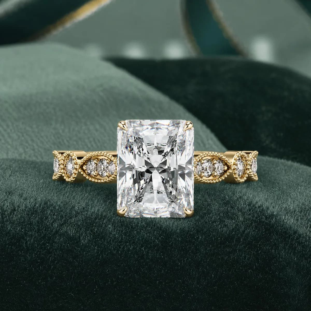 Radiant cut lab grown diamond vintage milgrain engagement ring in yellow gold resting on green velvet